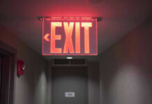 Red illuminated exit sign in a hallway.