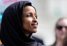 A woman wearing a black hijab looking thoughtfully during an outdoor event