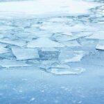 A frozen lake with cracked ice and blue hues