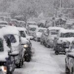 Traffic jam with cars covered in heavy snow during a snowstorm