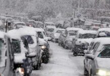 Traffic jam with cars covered in heavy snow during a snowstorm