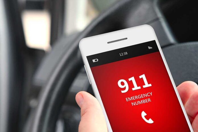 A smartphone displaying the emergency number 911 while held in a persons hand inside a car