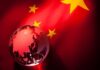 A globe illuminated against the backdrop of the Chinese flag