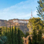 Hollywood sign on hill surrounded by trees and buildings.