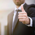 Person in suit giving thumbs up gesture.