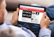 Person reading tablet with headline Scandal Unfolds.