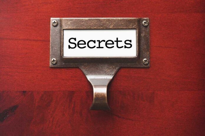 A label holder on a wooden surface with the word Secrets displayed