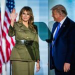 A couple at a political event, with one waving and the other looking on