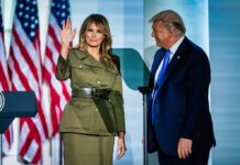 A couple at a political event, with one waving and the other looking on