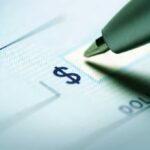 Close-up of a pen poised over a check with a dollar sign