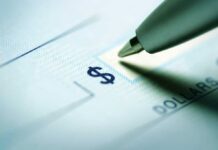 CANDIDATE Funnels Donor Money–Straight to Himself! Close-up of a pen poised over a check with a dollar sign