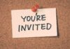 A note pinned to a corkboard that says YOU'RE INVITED
