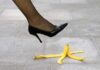 A high heel shoe poised above a banana peel on a tiled floor