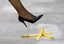 A high heel shoe poised above a banana peel on a tiled floor