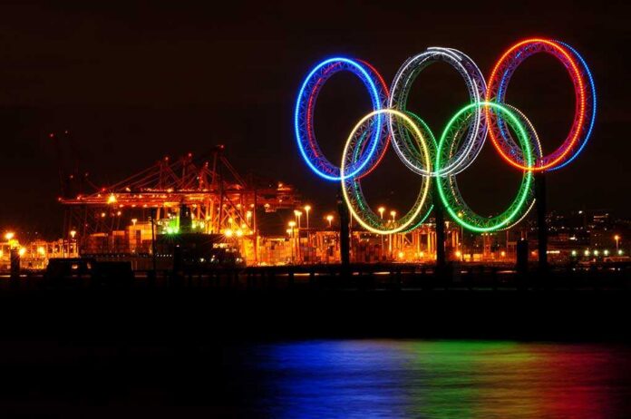 Illuminated Olympic rings displayed at night over a harbor