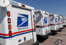 Row of USPS mail delivery trucks parked.