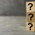 Three wooden blocks with question marks stacked.