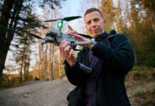 Person holding a drone in a forest.