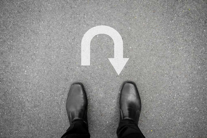 332468855 Feet in black shoes facing U-turn road marking.