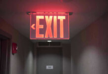 Red illuminated exit sign in a hallway.