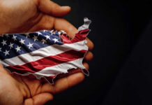 A hand holding a map of the United States adorned with the American flag