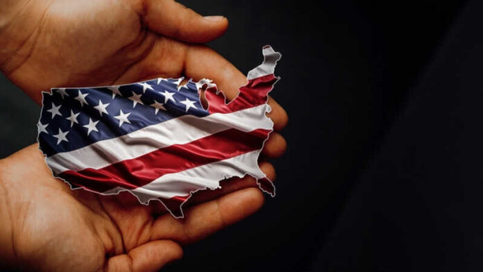 A hand holding a map of the United States adorned with the American flag