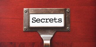 A label holder on a wooden surface with the word Secrets displayed