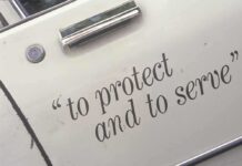 Close-up of a police car door with the phrase to protect and to serve