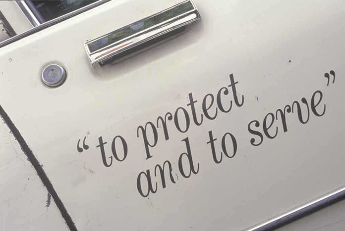 Close-up of a police car door with the phrase to protect and to serve