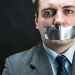 Judge MUZZLES Street Preaching Man in business attire with duct tape over his mouth, conveying a message about silence