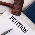 A gavel resting on a legal petition document with a pen and folder