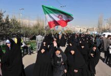 Group of women in black attire marching with an Iranian flag