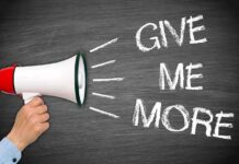 Congresswoman DEMANDS OUTRAGEOUS Reparations Scheme A hand holding a megaphone with the words GIVE ME MORE on a blackboard background