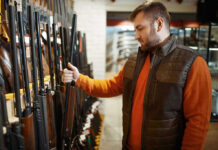 Man examining rifles in a store.