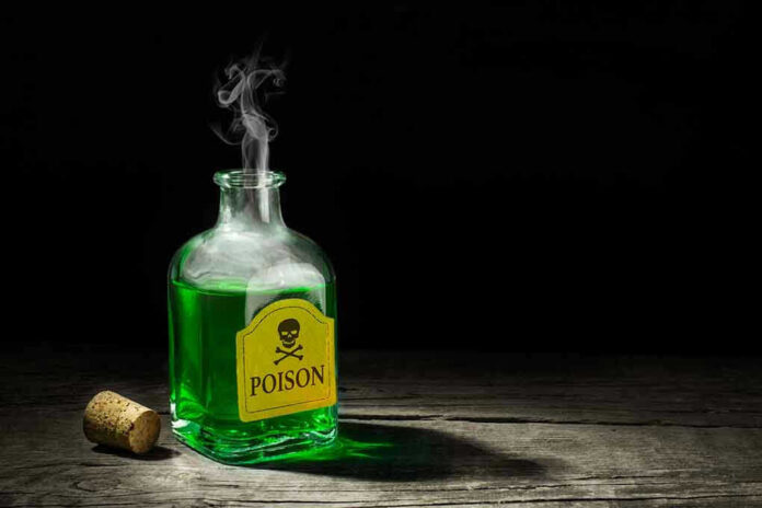 720129613 Green poison bottle with cork on wooden surface.