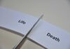 Scissors cutting a paper strip labeled 'Life' and 'Death'