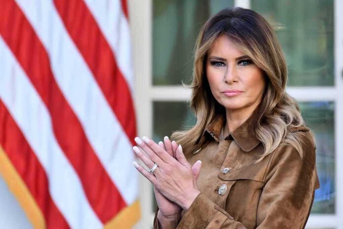 A woman in formal attire clapping in front of an American flag