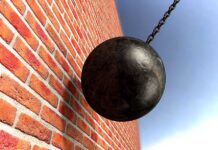 A wrecking ball suspended near a brick wall, suggesting demolition activity