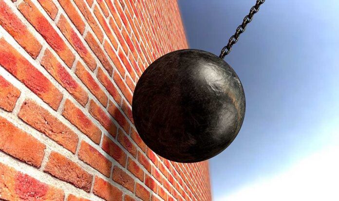 shutterstock_171754064.jpg A wrecking ball suspended near a brick wall, suggesting demolition activity