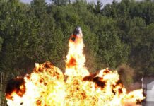 A large explosion with flames and smoke in an outdoor setting