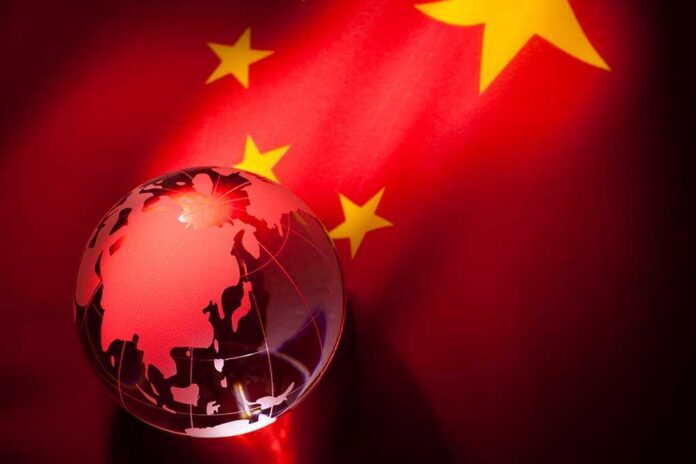 shutterstock_71395978.jpg A globe illuminated against the backdrop of the Chinese flag