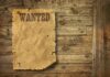 A vintage wanted poster pinned to a wooden wall