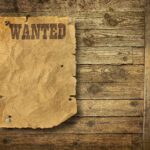 A vintage wanted poster pinned to a wooden wall