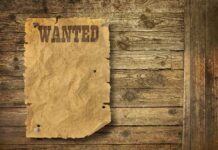 A vintage wanted poster pinned to a wooden wall