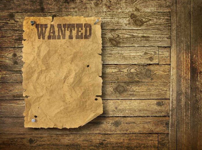 A vintage wanted poster pinned to a wooden wall