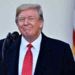Trump’s SHOCK Endorsement — Sitting SENATOR BLINDSIDED! Man in suit and tie speaking at podium.