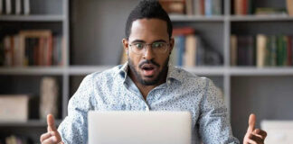 Man surprised while looking at laptop screen.