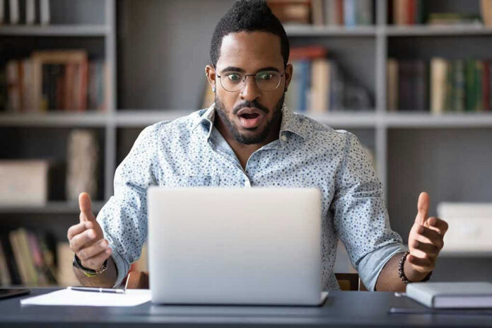 Man surprised while looking at laptop screen.