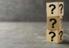 Three wooden blocks with question marks stacked.