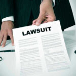 ELITE Media HIT With REVERSE Discrimination Lawsuit Person holding a document titled LAWSUIT in office.